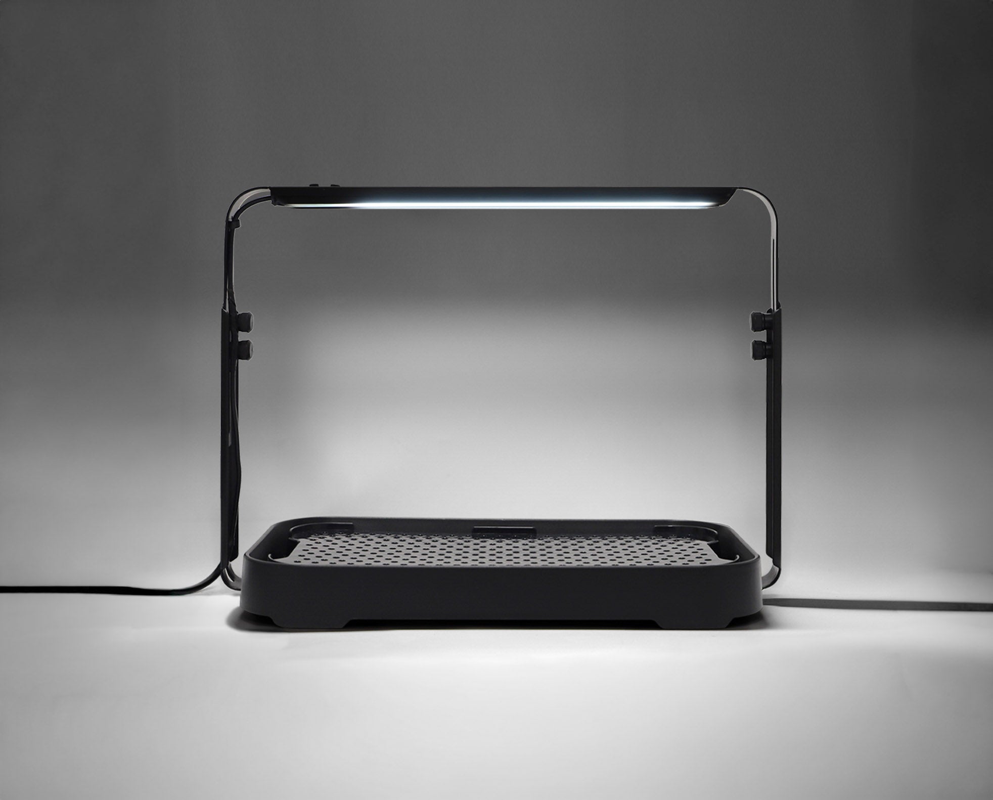 Black microgreen garden system with a height-adjustable LED grow light used for indoor gardening.